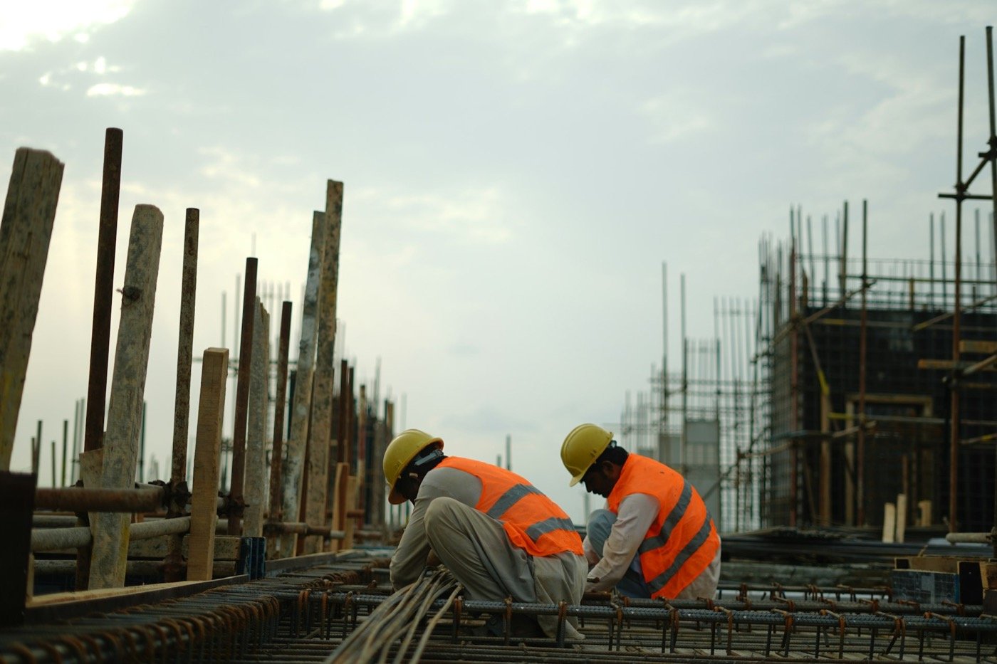 Zwei Bauarbeiter mit Helm und Warnweste bei der Arbeit